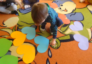 Chłopiec przygląda się rozłożonym na dywanie serduszką.